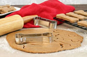 How Do You Make Dog Biscuits For Dog with Dog biscuit dough with rolling pin and bone shaped cookie cutters on a silicone mat