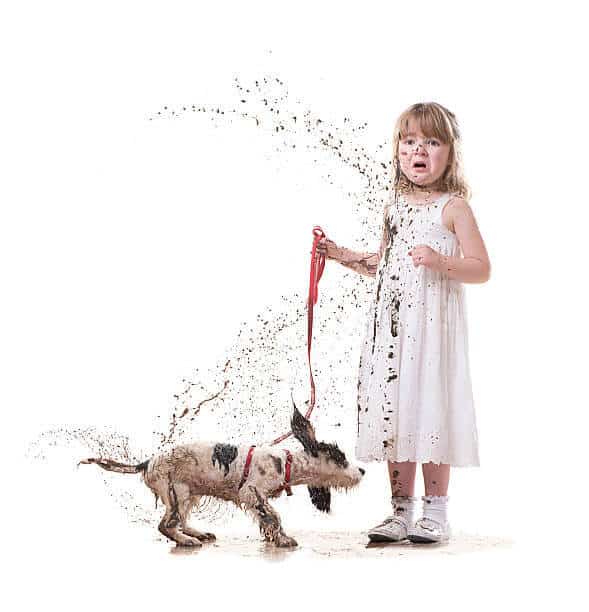 little girl takes a puppy for a walk in her best dress and the puppy shakes its self covering her in mud
