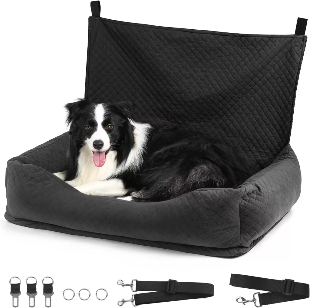 Small black and white dog laying in a black car seat against a white background.